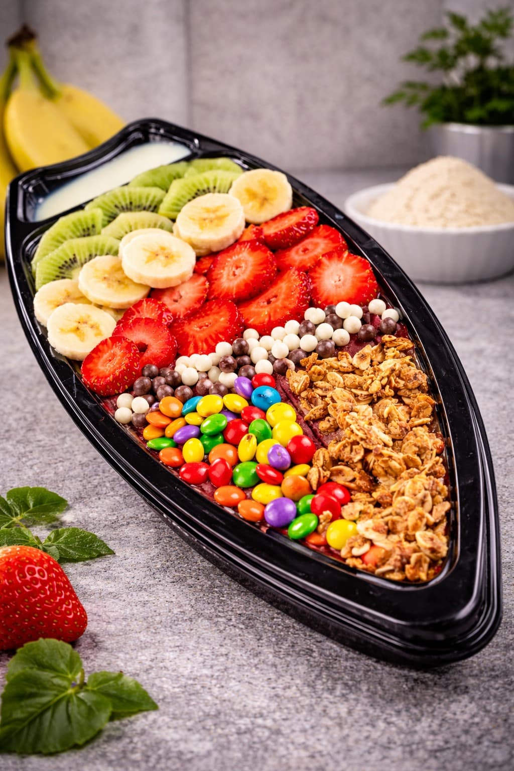 An açaí boat topped with kiwi, banana, strawberries, granola and candy