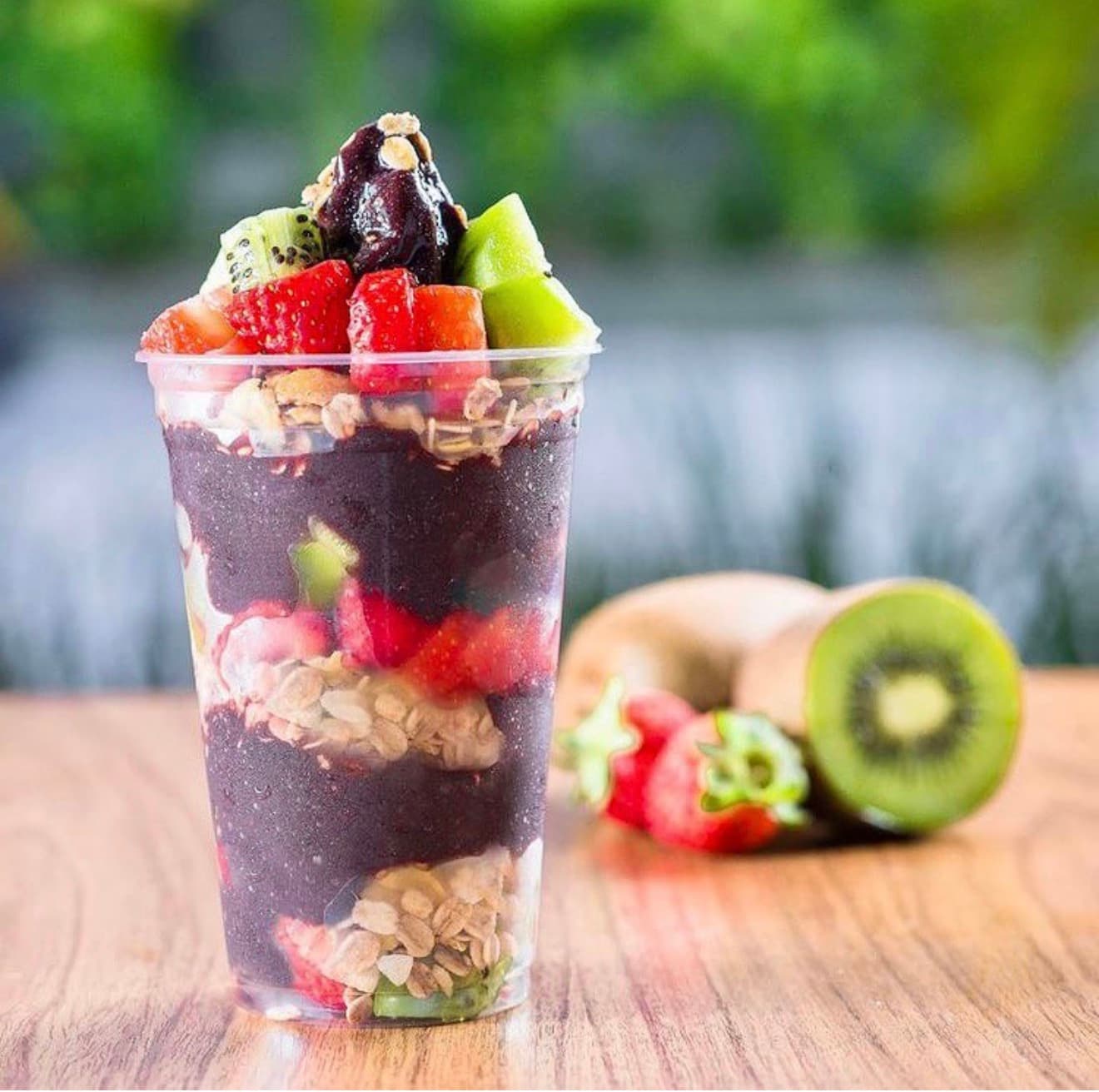 A tall cup layered with açaí, strawberries, kiwi and granola